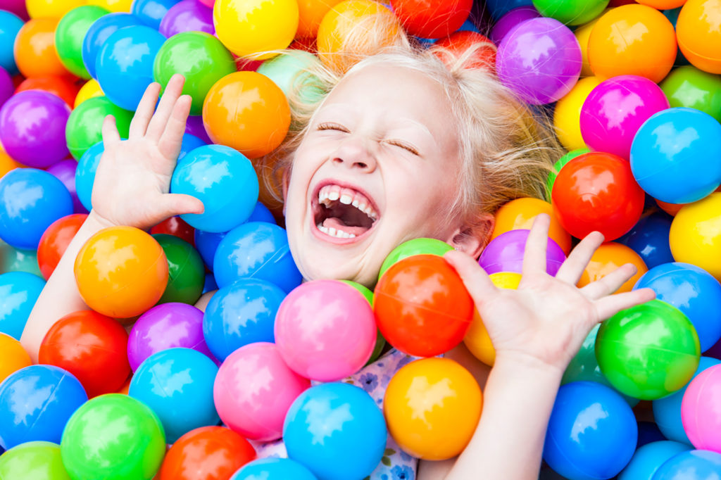 Blond Girl Child Having Fun Playing in Colored Balls